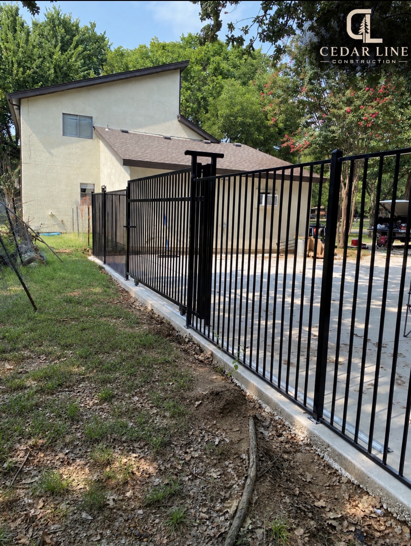 Black metal fence on a concrete footing by a driveway