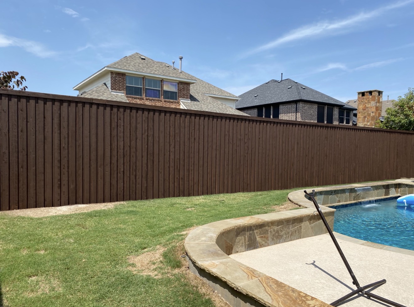 Dark stained cedar fence beside a stone pool deck