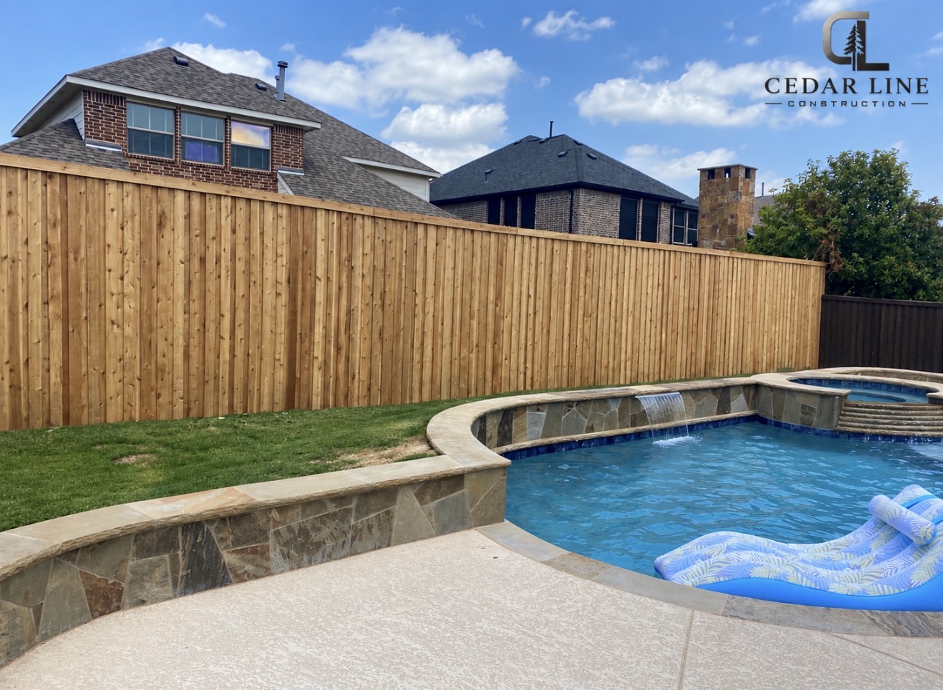Natural cedar fence beside a stone pool deck