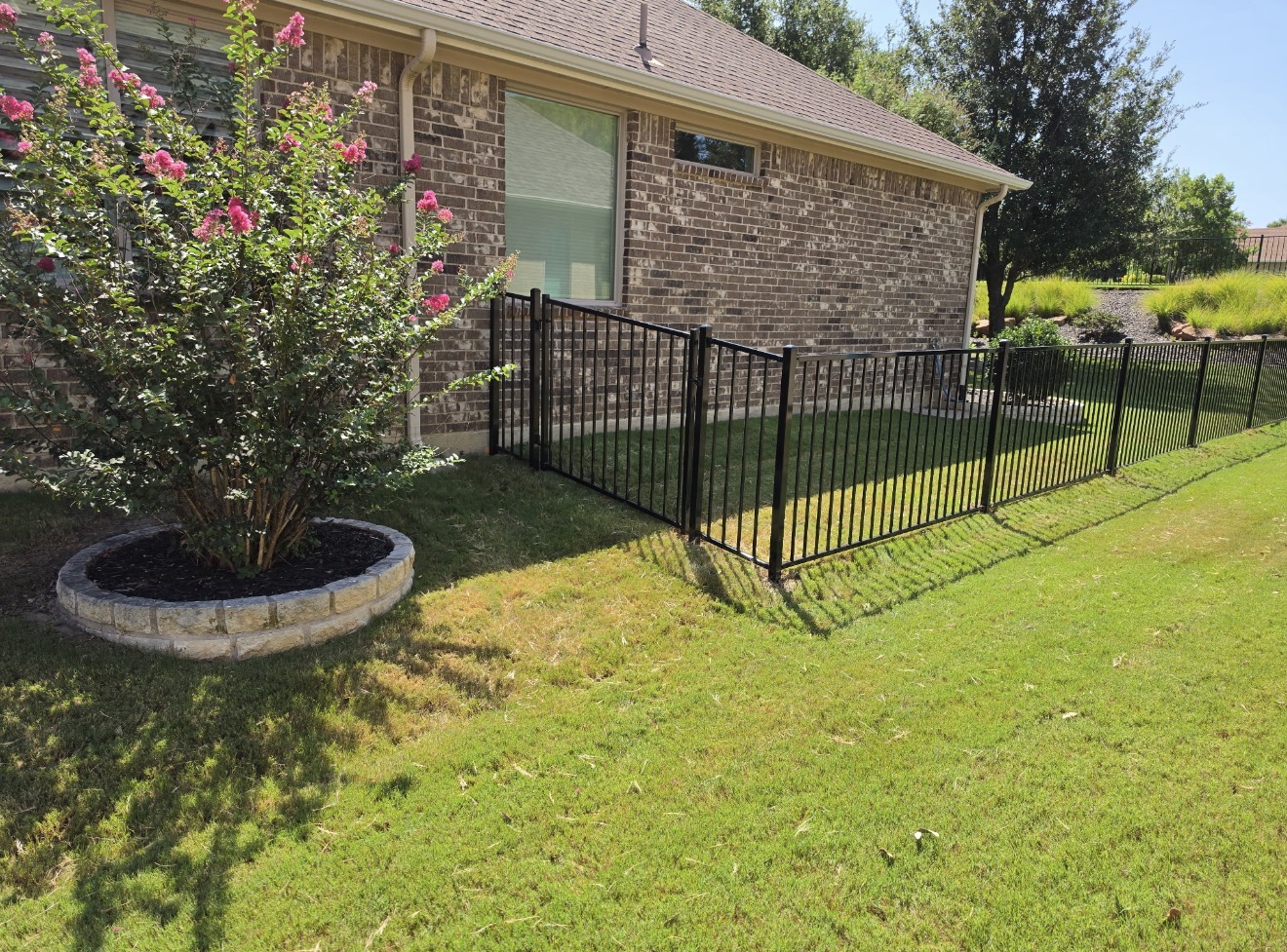 Black metal fence corner with a stone tree ring